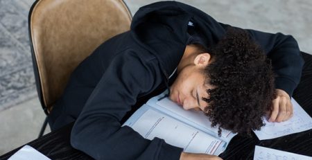 Man is asleep with his head on papers