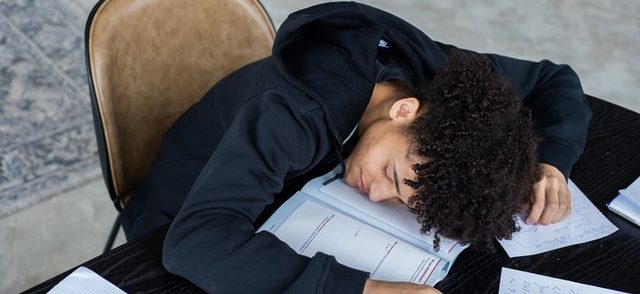 Man is asleep with his head on papers